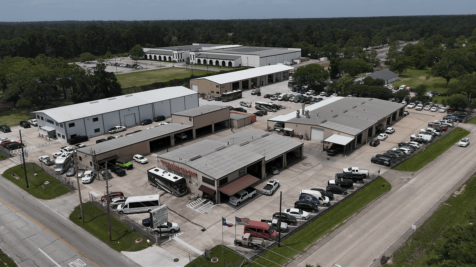 Professional automotive repair shop exterior with service vehicles at Woodlands Car Care & Collision Center